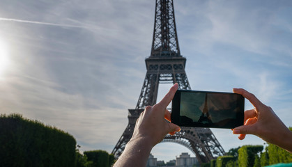 Famous popular tourist place in the world. Tourist in Paris visiting landmark sightseeing in France, woman taking photo on mobile phone.