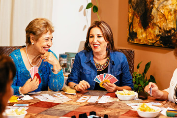 Senior women playing cards at table in living room