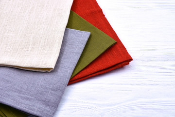Colorful linen towels on a white wooden background.