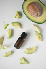 Natural organic avocado oil in a dark glass bottle on a light background.
