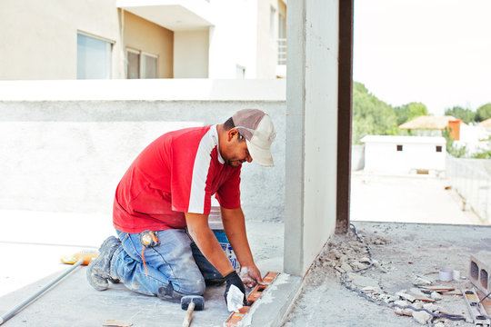 Bricklayer using level on worksite