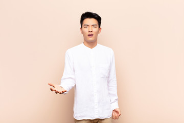 young chinese man looking angry, annoyed and frustrated screaming wtf or what‚Äôs wrong with...