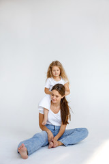 Happy baby daughter weaves pigtails to soy mom. Photo on a white background. Happy family concept