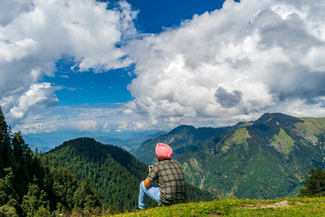 Fototapeta na wymiar Jalori Pass, Himachal Pradesh, India; 20-September-2019; a solo trekker enjoying the mountain view, Jalori Pass, Himachal Pradesh, India