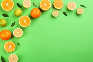 Flat lay composition with tangerines and different citrus fruits on green background. Space for text