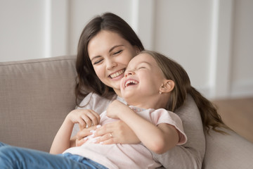 Smiling mom and little daughter have fun playing together