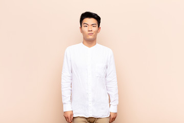 young chinese man feeling confused and doubtful, wondering or trying to choose or make a decision...