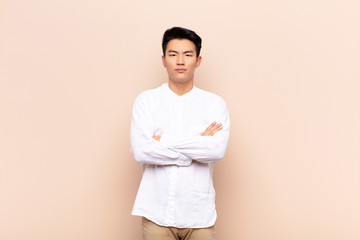 young chinese man feeling displeased and disappointed, looking serious, annoyed and angry with...