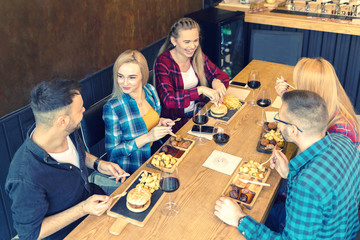 Young people dinning and having fun drinking red wine together at pub party – happy friends eating tasty food
