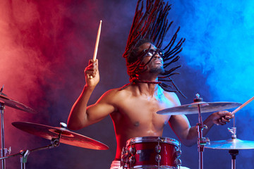 professional african male with head up playing on drums isolated over smoky neon space