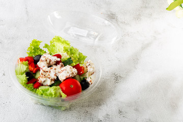Greek salad of fresh cucumber, tomato, sweet pepper, lettuce, red onion, feta cheese and olives with olive oil isolated on white marble background.   Selective focus. Horizontal Healthy food, top view