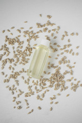Natural organic sunflower oil in a bottle on a light background with seeds.
