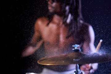 Fototapeta na wymiar close-up of wet drums with water drops. cropped handsome muscular african man beating, hitting on drums, wearing eyeglasses, in dreadlocks.