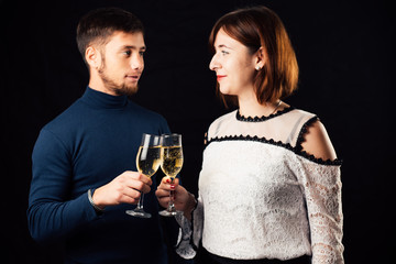 Girl and man on a black background with glasses of champagne