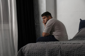 Depressed overweight man on bed at home