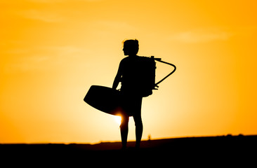 Silhouette of a kitesurfer packing outfit for sunset. El Médano, Tenerife / Spain