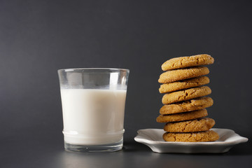 A glass of cold milk sits next to a stack of gingerbread cookies on a white plate; copy space