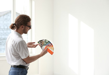 Professional interior designer with color palette in empty apartment. Space for text