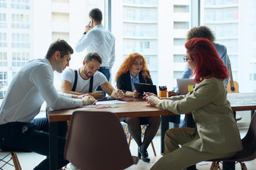 business crew working with new startup project. Idea presentation, analyze marketing plans. Team of creative colleagues in modern conference office, panoramic windows background.Creative process