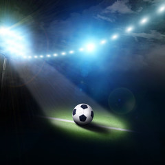 Naklejka premium Center of a football field with a ball and stadium lights