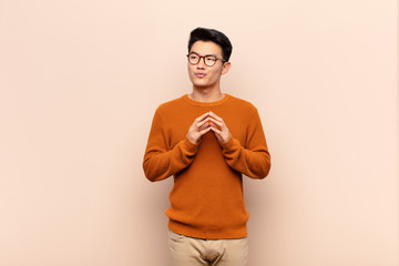 young chinese man scheming and conspiring, thinking devious tricks and cheats, cunning and...