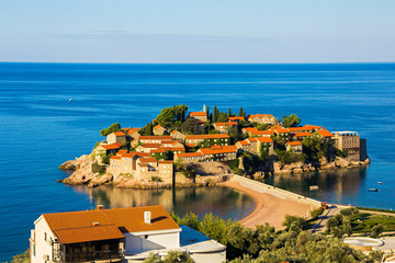 Obraz premium view of one of a beach of Budva town and the island of Sveti Stefan with famous hotel resort in Adriatic sea, Montenegro
