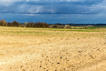 Late autumn. Large plowed field.  Meadows  and village in the background.  Dairy farm. Podlasie, Poland.