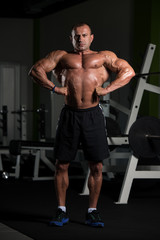 Fototapeta na wymiar Mature Muscular Man Flexing Muscles In Gym
