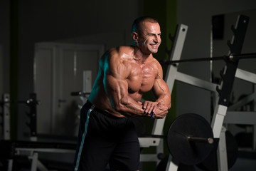 Fototapeta na wymiar Mature Bodybuilder Posing Biceps After Exercises