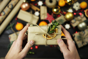 A man holds a Christmas wrapped gift, hands close-up