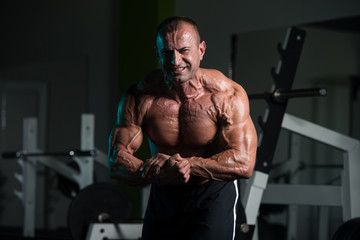 Fototapeta na wymiar Mature Muscular Man Flexing Muscles In Gym
