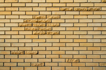 Obraz premium Wall of yellow silicate brick. There are several decorative bricks with a chipped rustic edge. Background. Texture.