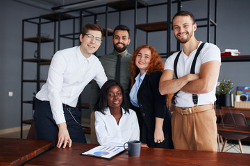 Portrait of joined group of people working together, multi-ethnic business co-working in modern office. Posing and confidently look at camera