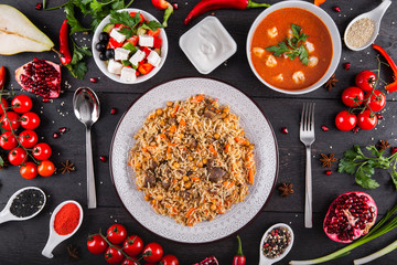 The concept of Eastern asian festive cuisine. Assorted Uzbek food set, pilaf, samsa, lagman, manti, shurpa restaurant concept Eastern arabic new year and Christmas dish from lamb served cookware.