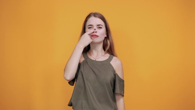 Young funny beautiful caucasian woman wearing nice shirt puffing cheeks and keeping fingers on with funny face. Mouth inflated with air, crazy expression