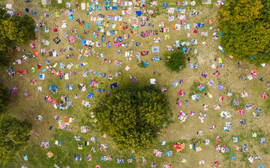 Top view of a crowd of people resting on the grass in a water park. People sunbathe and relax on...