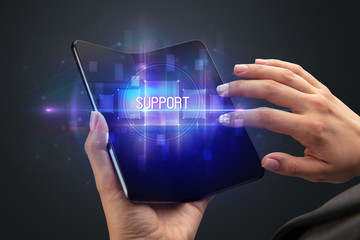 Businessman holding a foldable smartphone with SUPPORT inscription, new technology concept