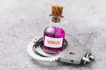 Bottle with a virus and handcuffs on a table. Punishment for the illegal manufacture of toxic...