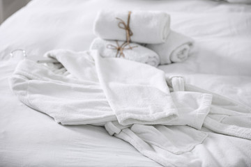 Obraz na płótnie Canvas Clean soft bathrobe and towels on bed