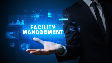 Hand of Businessman holding FACILITY MANAGEMENT inscription, business success concept