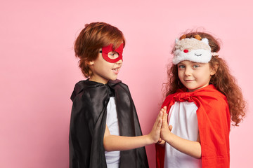 Attractive caucasian girl and boy clap hands, girl look at camera. isolated over pink background