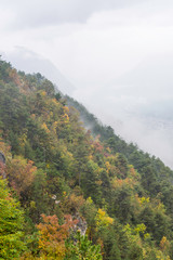 sunny autumn afternoon mountain scenery. trees in fall foliage on the hillside. green grassy meadow. ridge in the distance. bright weather with clouds on the cloudy sky
