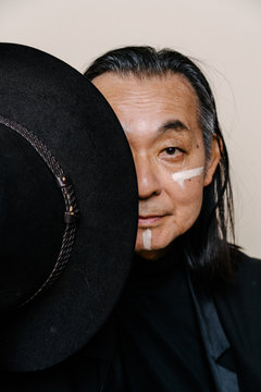 帽子で顔を隠した、白い化粧をしたシニア男性のポートレート