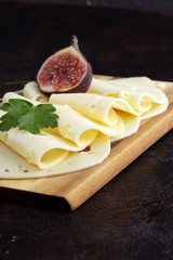 cheese slices on wooden tray with parsley. gauda cheese