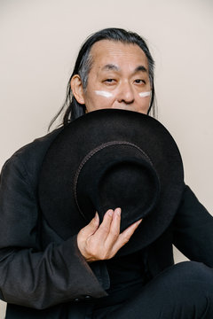 帽子で顔を隠した、白い化粧をしたシニア男性のポートレート