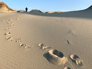 Feetprints in white sand, man and blue sky