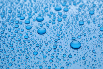 Water drops on light blue background, closeup view