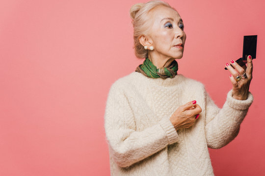 コンパクトで化粧を確認するシニア女性