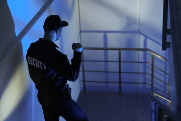 Male security guard with flashlight on stairs in darkness - obrazy, fototapety, plakaty