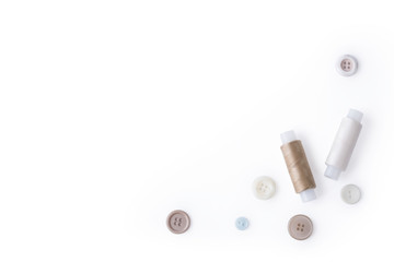 Flat lay composition from a set of scattered buttons and spools with colored threads with an empty place for text on a white background